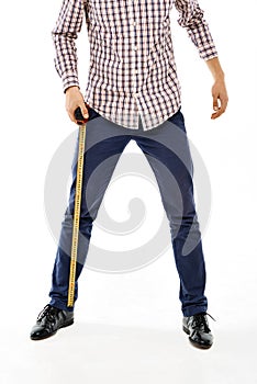 Close-up confident young man with tape measure wearing casual plaid shirt and blue jeans. Straddle. Isolated photo