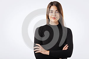 Close-up of confident young woman with folded arms against white background