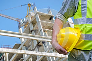 Close-up construction worker holding hard hat with background of