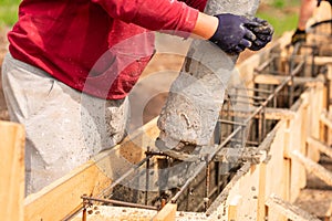 Close up of construction worker laying cement or concrete into the foundation formwork with automatic pump