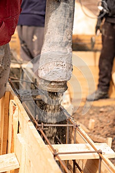 Close up of construction worker laying cement or concrete into the foundation formwork with automatic pump