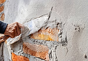 Construction worker's hands leveling fresh concrete on a brick wall