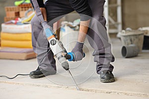 Construction worker using rotary hammer on the floor