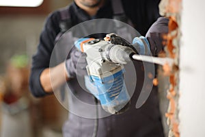 Construction worker using rotary hammer to wreck wall