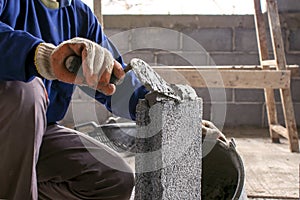 Close-up of construction workers using cement trowel on the brick to build walls.