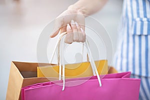 Close up of consumerism young woman holding hand many shopping bag in fashion boutique after buying presents while walking along t