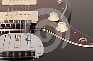 Close up of control tone  on  black electric guitar, studio shoot. Red tortoise shell pickguard, alder body, two single coil