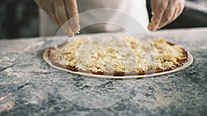 Close up for cook& x27;s hands putting cheese on the pizza Four Cheeses.Chef adding the ingredients to the pizza