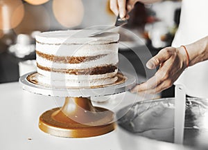 Close up of cook smearing butter cream on chocolate cake.