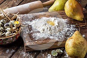 Close up. Cooking autumn pear cake. Making dough from quail eggs and flour on a brown wooden board