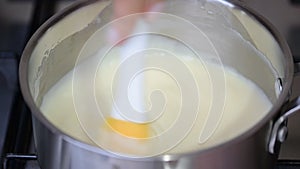 Close up of cooking creme patissiere custard in a small pan with eggs, sugar, milk and cream