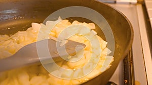 Close up of cooking onions in a pan stirring with a spoon