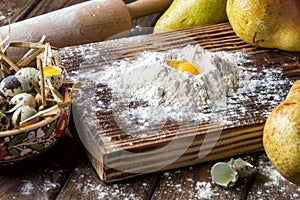 Close up. Cooking traditional pear cake. Making dough from quail eggs and flour on a brown wooden board