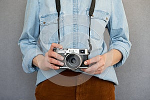 Close up of cool woman wearing casual clothes holding a vintage style camera