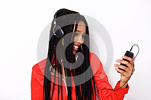 Close up cool young african woman listening music with mobile phone and headphones on white background