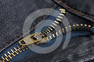 Close-up of a copper color zipper with black jeans
