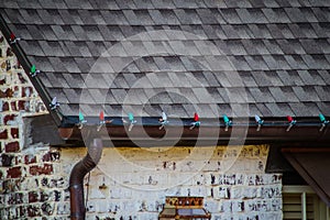 Close-up of copper guttering of brick house with screen and mounted red and green Christmas decortion lights