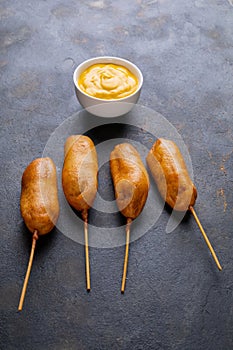 Close-up of corn dog with mustard sauce in bowl on table