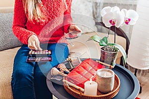 Close up of cosmetic bag with beauty products and brushes. Woman applying makeup at home holding mirror