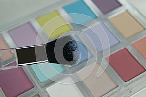 Close-up of cosmetic brush on eye shadow palette background