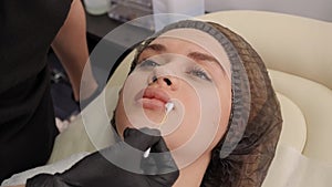 Close-up cosmetologist moistens the lips of a woman with cream. Permanent makeup
