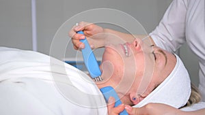 A close-up of a cosmetologist performs an electrostimulation face massage. Facial massage.