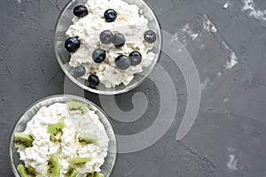 Close - up of cottage cheese in glass bowls with fillers on a gray background