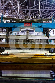 Close up of a cotton thread weft loom machine in a conveyor belt factory