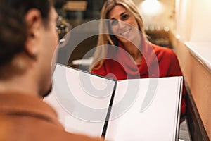 close up of couple with blank menu card choosing dishes at restaurant, with copyspace for your individual text