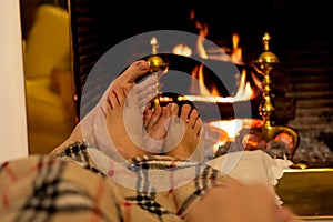 Close up of couple feet warming up by the fireplace in winter vacation and happy moments together