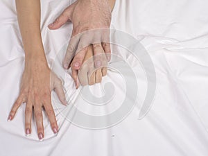 Close up of couple hands lie on bed in bedroom, lovers have intense sex or making love feeling orgasm and satisfaction