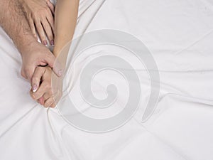 Close up of couple hands lie on bed in bedroom, lovers have intense sex or making love feeling orgasm and satisfaction