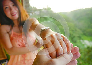 Close up couple hands man holding Asian happy fiance hand with diamond engagement ring on her finger after wedding proposal at