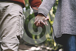 Close up of couple holding hands with green forest nature background. Concept of love and relationship with adults man and woman