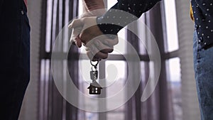 Close-up couple holding hands with new home keys