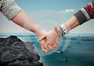 Close-up of couple holding hands with sea in background