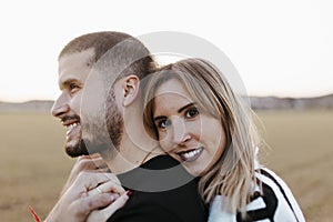 Close up couple hugging and looking at camera in the countryside embraced. Boyfriend and girlfriend in love