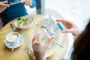 Close up of couple picturing food by smartphone