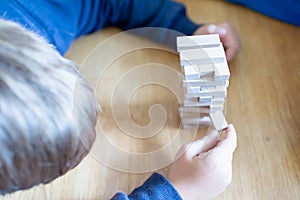 Close up couple playing jenga indoor on table.Boy lying down and playng