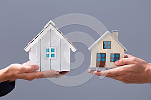 Close-up Of Couple`s Hand Holding Different Miniature Houses