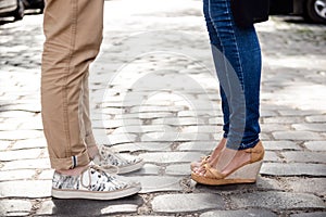 Close up of couple's legs in keds standing at street.