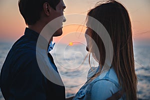 Close up of couple watching the sunrise at the beach summer time, seashore summer beach at yellow blue evening horizon sea, sunset