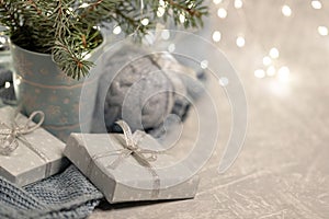 Close up cozy Christmas composition with mug fir branches, Xmas lights, DIY gift boxes, knitted Xmas ball, bokeh