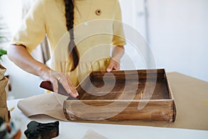close-up of a craftswoman sanding a wenge-colored box