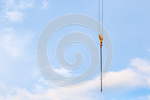 Close up crane with a hook on the end in the blue sky background