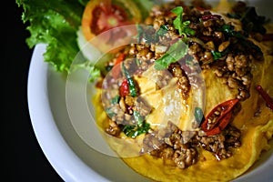 Close up Creamy Omelette with stir-fried pork and basil on steamed rice In a white circular dish
