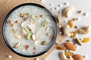 Close-up of Creamy Sabudana Kheer Garnished with dry fruits. Indian delicious dessert. Served in a black bowl. Top View on white photo