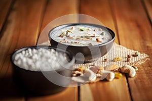 Close-up of Creamy Sabudana Kheer Garnished with dry fruits. Indian delicious dessert. Served in -black ceramic bowl. Top View