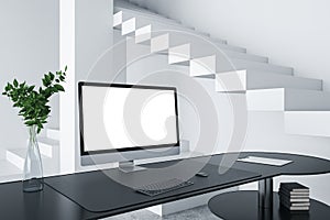 Close up of creative designer desktop with empty white computer screen frame, decorative items and modern interior in the