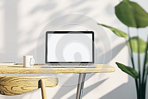 Close up of creative designer office desktop with empty white laptop screen with mock up place in frame, concrete wall background